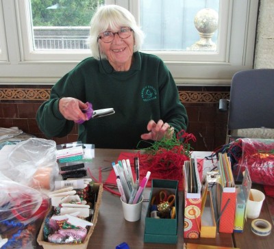 Lady sat at table with an assortment of arts and craft activites 